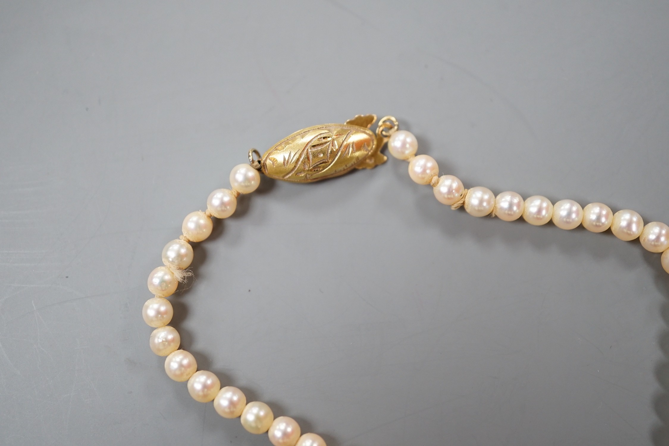 A modern cultured pearl and diamond cluster set drop 'acorn' pendant, overall 23mm on a cultured pearl necklace with 18k clasp, necklace 36cm.